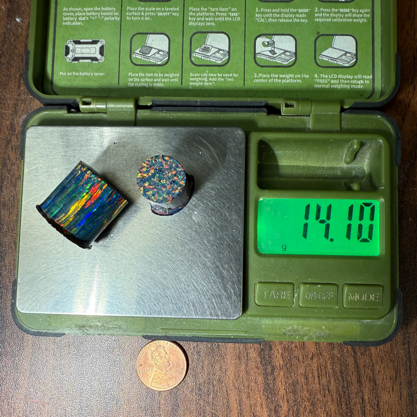 Two opal cores on a digital scale with a penny for size comparison on a wooden surface.