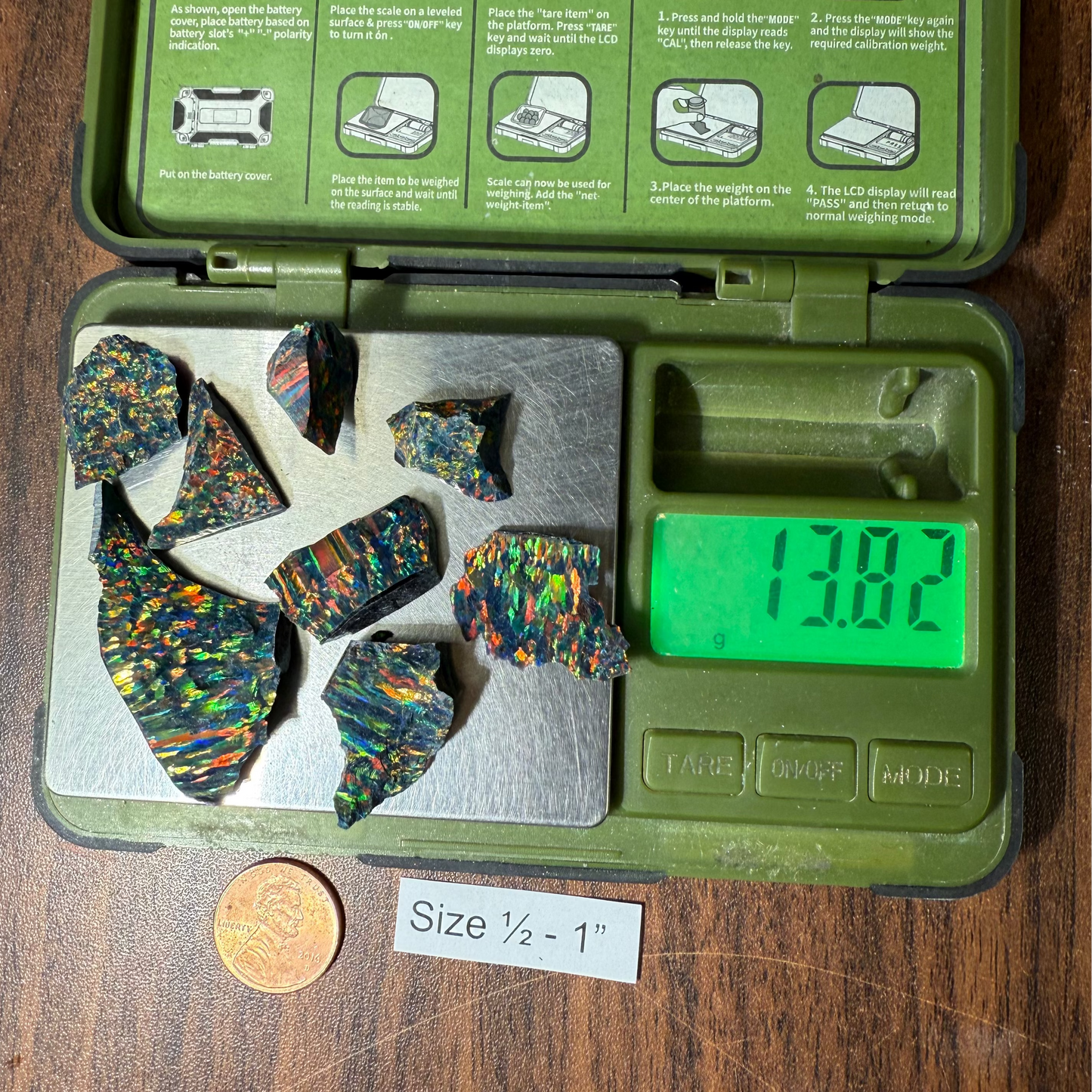 Green digital scale with 1/2 - 1" opal and a penny for size reference on a wooden surface.