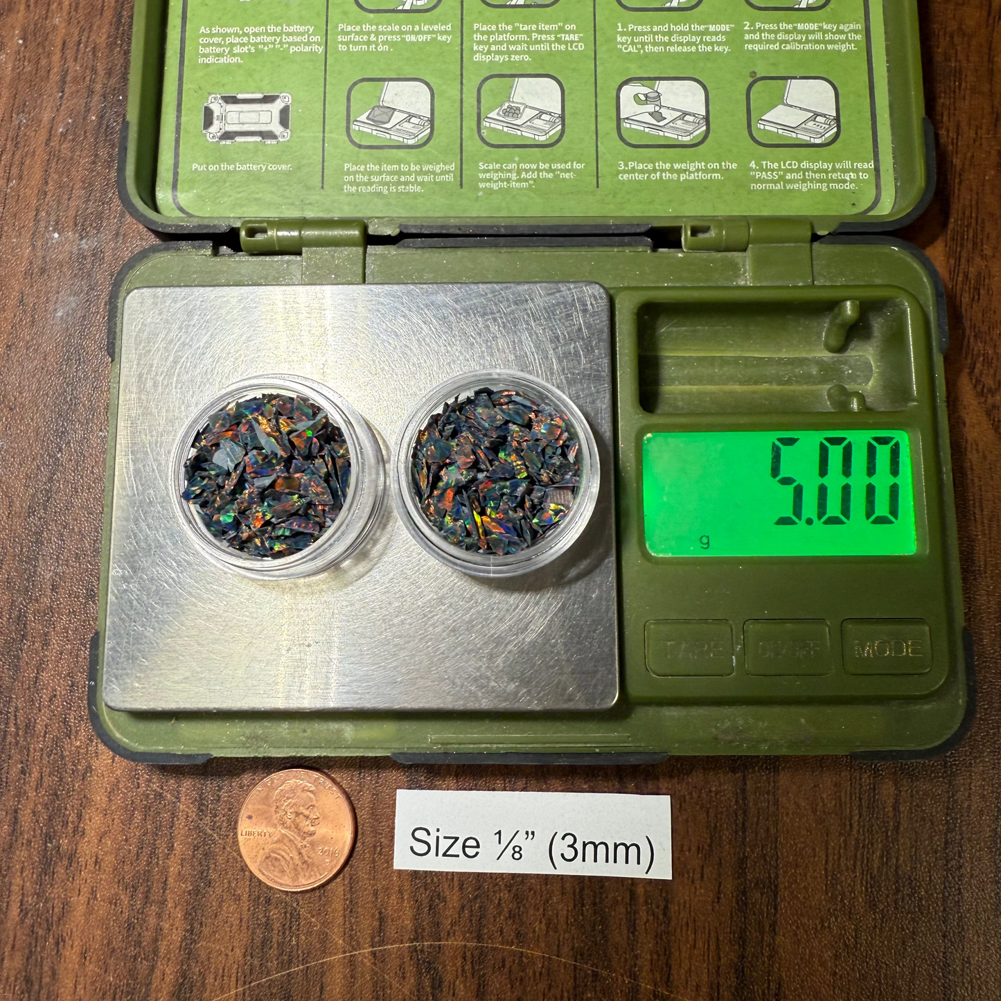 Small digital scale with two small containers of 1/8" opal on a wooden surface.
