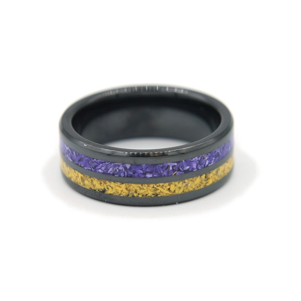 Black ceramic double-channel ring inlaid with purple and yellow Colorstone, lying flat on white