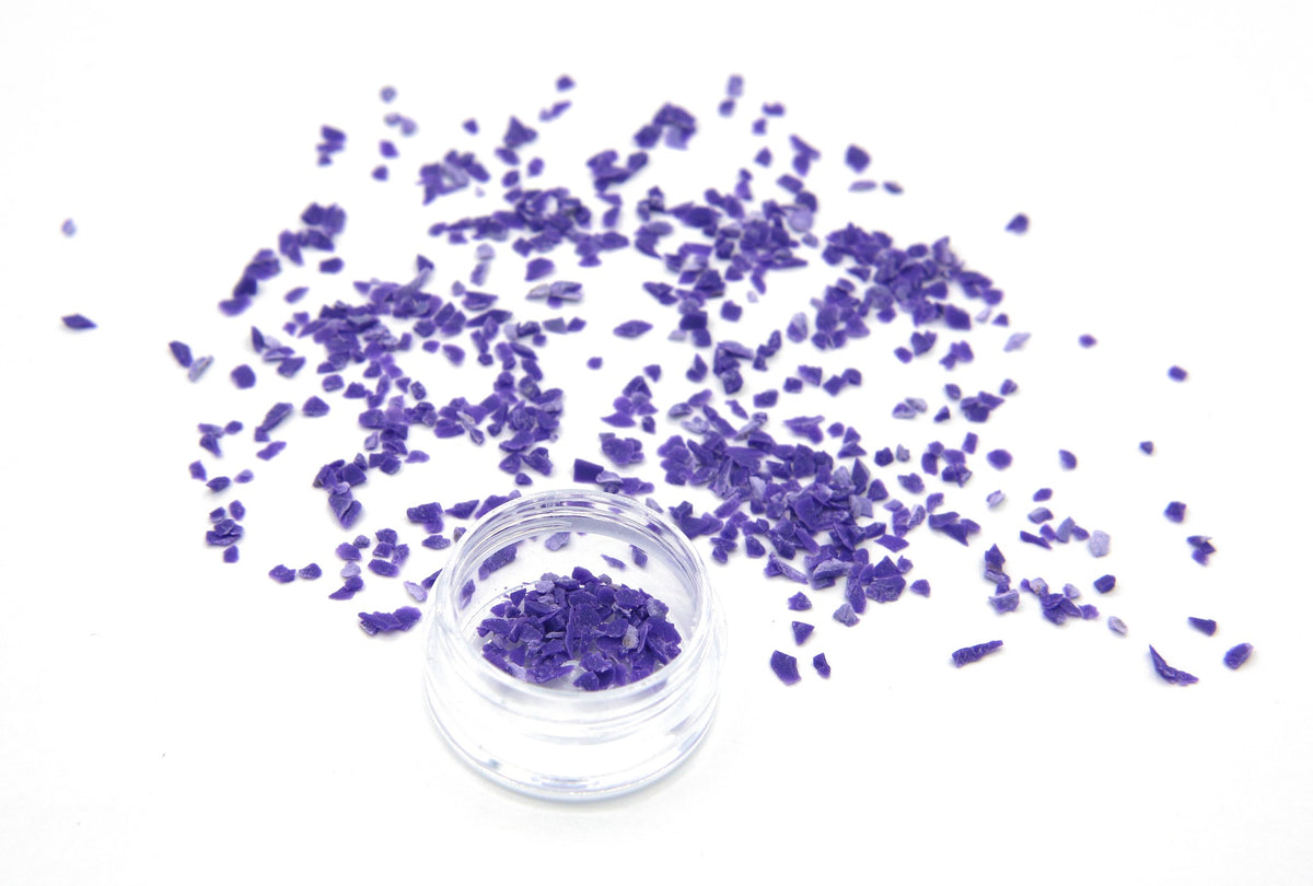 Purple Colorstone fragments scattered on white, with a small jar of the crushed stone