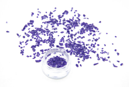 Purple Colorstone fragments scattered on white, with a small jar of the crushed stone