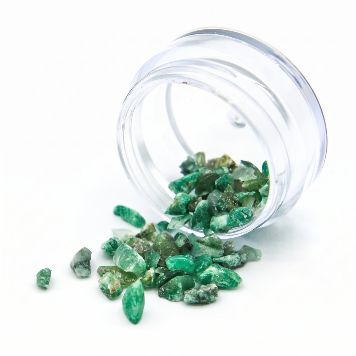 Emerald fragments spilling from a tipped 2 g jar