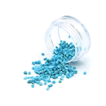 Turquoise fragments spilling from a tipped 2 g jar