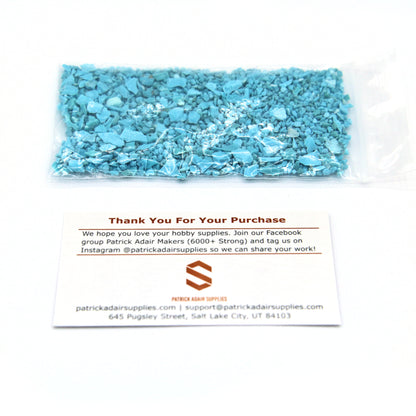 A 25 g bag of turquoise fragments next to our thank-you card, for scale